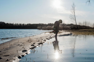 Young boy playing in the water at the sunny beach in winter