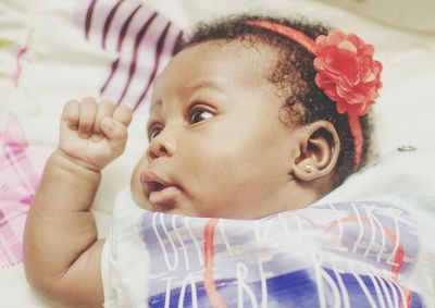 Close-up portrait of cute baby girl on bed