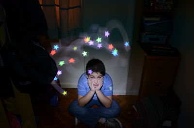 Portrait of sad boy against star shape light paintings at home