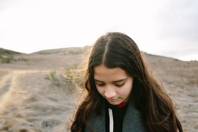 Portrait of young woman looking away against sky