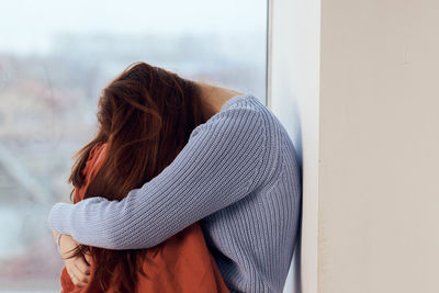 Rear view of woman standing against window