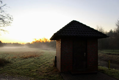 House on field against sky during sunset