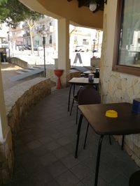 Empty chairs and tables at sidewalk cafe in city