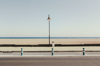 Street light against beach against clear sky on sunny day