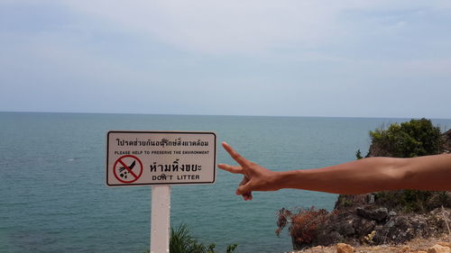 Low angle view of woman hand by sea against sky