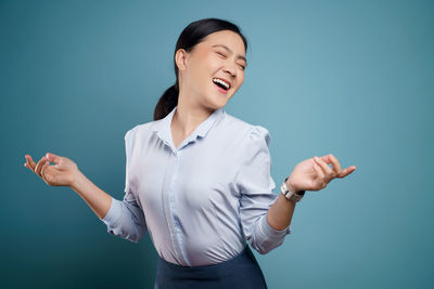 Smiling young woman standing against blue background