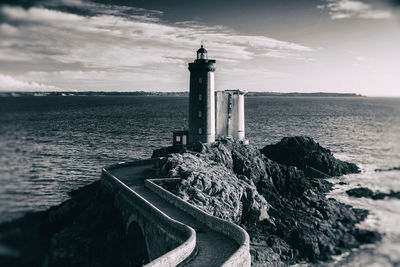 Lighthouse by sea against sky