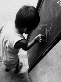 Side view of boy drawing on blackboard