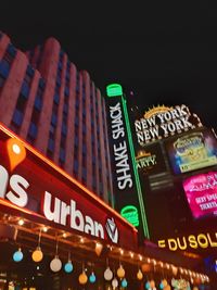 Low angle view of illuminated information sign in city at night