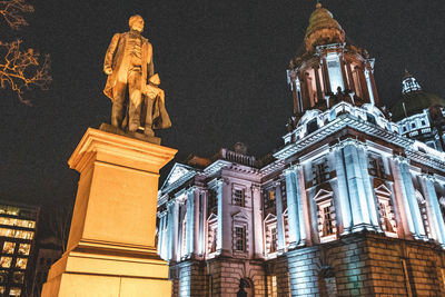 Low angle view of statue in city at night