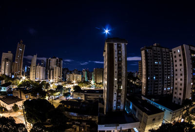 Illuminated buildings in city against sky at night