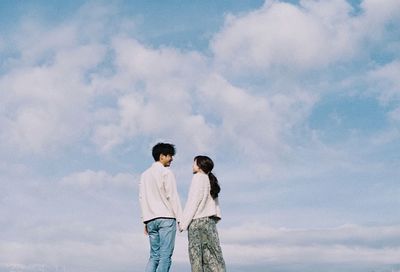 Low angle view of couple standing against sky