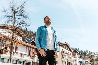 Portrait of a handsome hipster man in a jean jacket. a man in a big city on the street