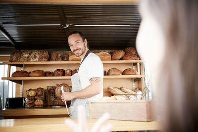 Smiling male owner selling fresh breads in concession stand