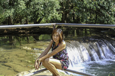 Portrait of beautiful woman sitting with stream in background