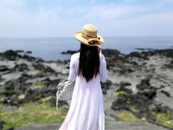 Rear view of woman standing on seashore