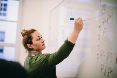 Teacher writing on whiteboard in classroom