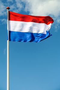 Low angle view of dutch flag waving against blue sky