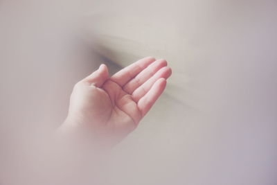 Cropped image of hand holding face over white background