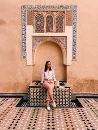 Young woman sitting on seat against historic building