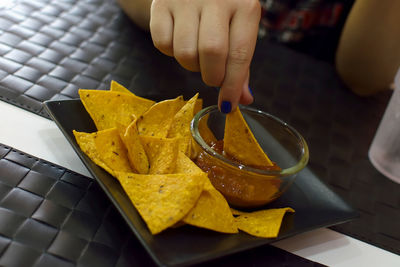 Cropped hand of woman eating nacho chips