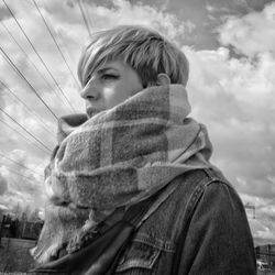 Portrait of young woman looking at camera against sky