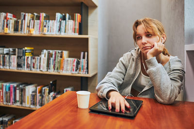 Young woman using mobile phone at library