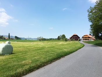 Scenic view of road by buildings against sky