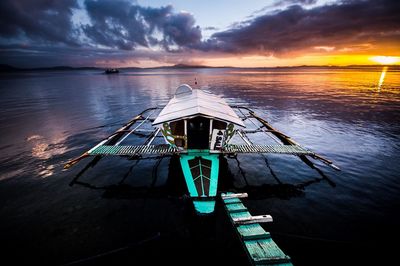 Boat in calm sea at sunset