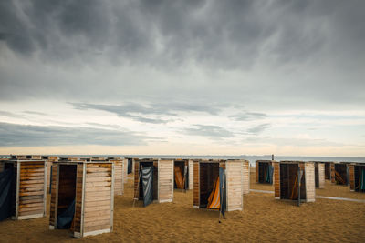 Hooded chairs on beach against sky