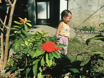Girl looking away while standing by flowering plants