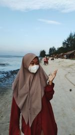 Midsection of person standing at beach against sky