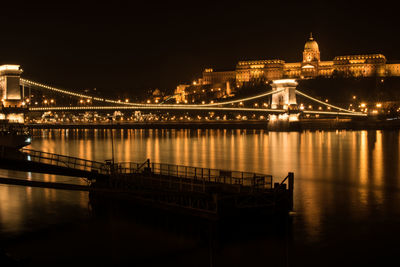 Illuminated bridge over river at night