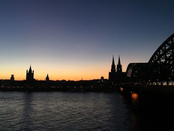 River in city against clear sky during sunset