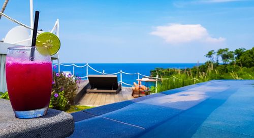 Potted plant on table by swimming pool against sky