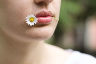 Close-up of woman with flower in mouth