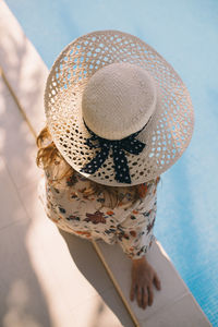 Close up top view of woman with hat sitting by the pool