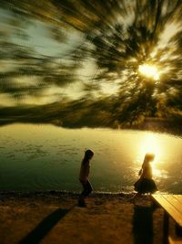Silhouette man by lake against sky during sunset
