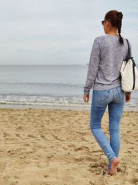 Rear view of woman on beach against sky