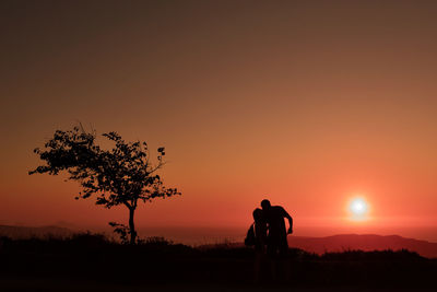 Silhouette people on field against sky during sunset