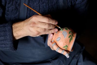 Close-up of man painting clay container