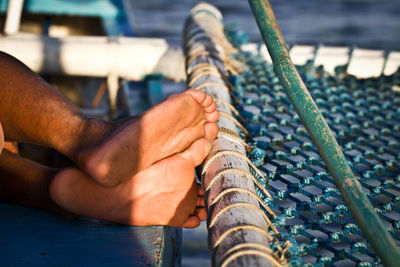 Low section of man relaxing by fishing net on boat