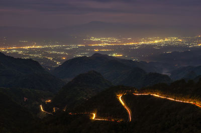Aerial view of illuminated road on mountain against sky at night