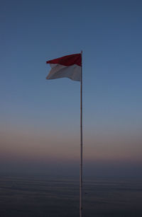 Low angle view of flag against clear sky during sunset