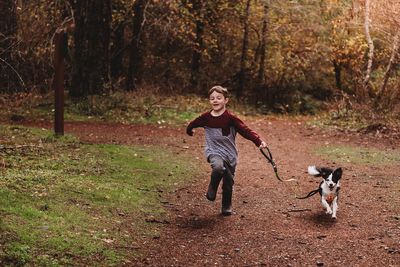 Full length of a boy with dog in the background
