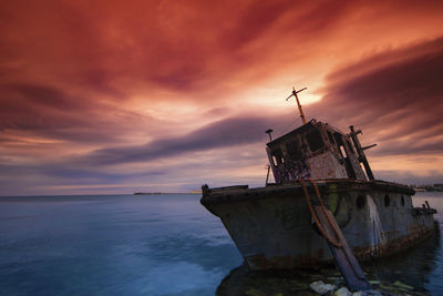 Fishing boat in sea against sky during sunset