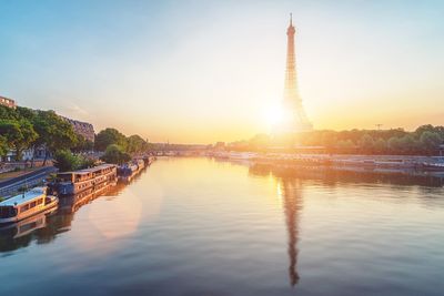 Scenic view of eiffel tower by river during sunset