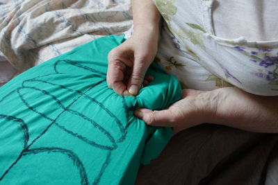 Midsection of woman sewing fabric at home