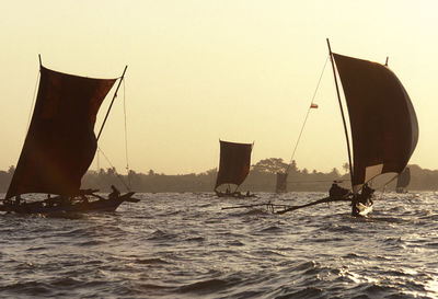 Boats sailing on sea during sunset