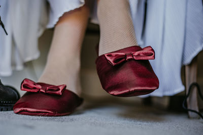 Low section of woman wearing shoes at home